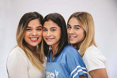 girl with braces smiling with her mom and sister