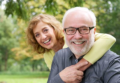 man with dental implants smiling with his wife